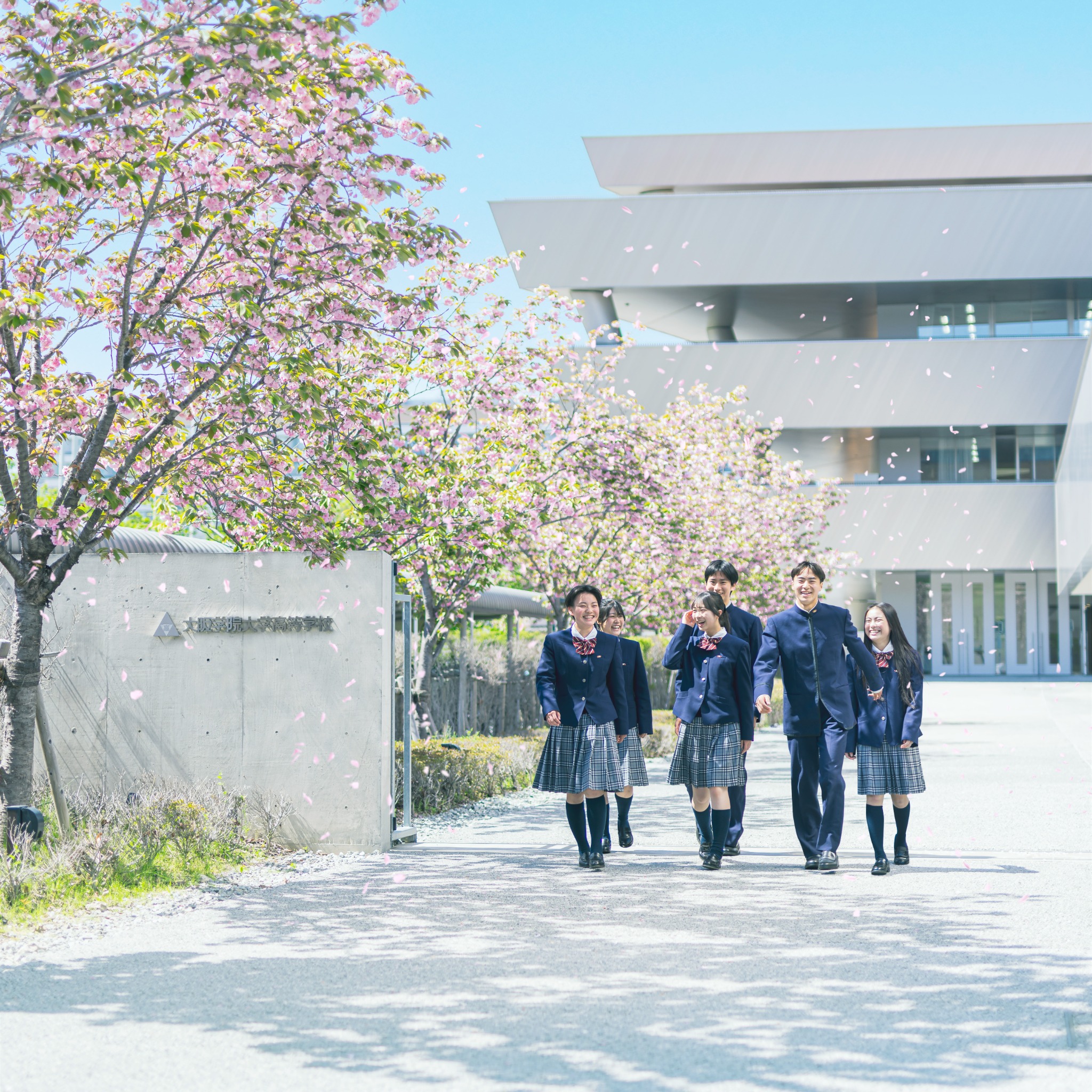 桜の咲く校舎前を歩く大阪学院大学高等学校の生徒たち